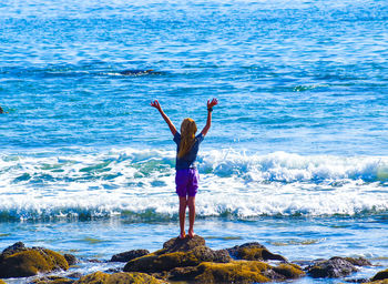 Rear view of woman standing by sea