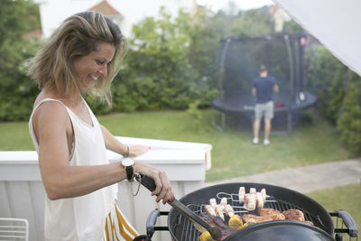 Smiling woman preparing food on barbecue