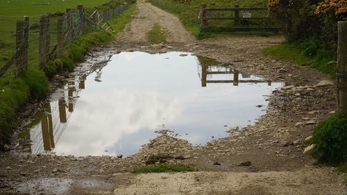 Reflection of clouds in puddle on canal