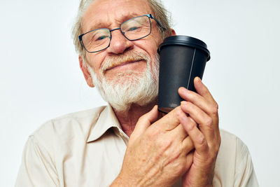 Senior man holding coffee cup against white background