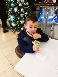 Cute boy eating while sitting on table