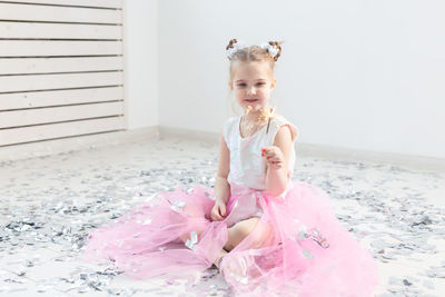 Portrait of cute girl sitting against pink wall