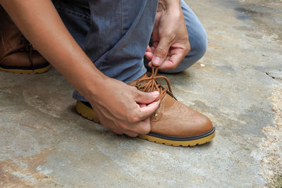 Low section of person tying shoelace