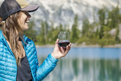 Young active attractive woman enjoys red wine at the lake.