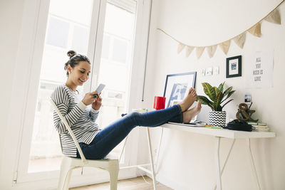 Woman at home laying feet on table looking at cell phone