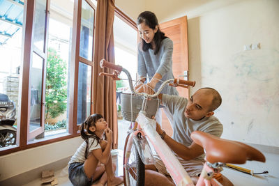 Father and mother assembling bicycle at home