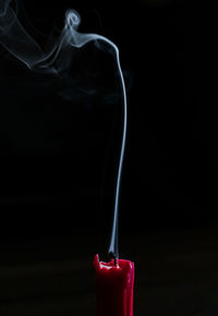 Close-up of burning candle against black background