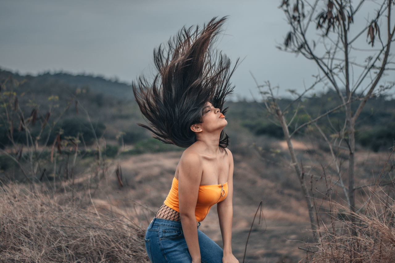 real people, one person, lifestyles, leisure activity, focus on foreground, field, three quarter length, standing, land, nature, plant, sky, day, side view, child, environment, clothing, outdoors, childhood, hairstyle, wind