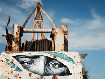Close-up of rusty machine part against sky