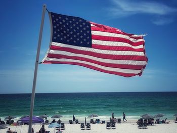 Flag people on beach against sky