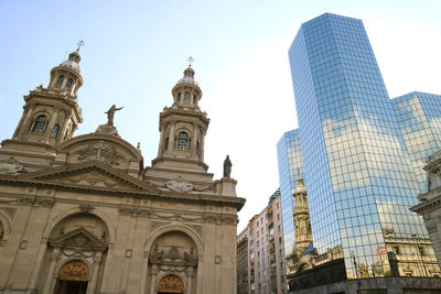 Metropolitan cathedral of santiago reflected in the glass clad facade of the modern building, chile