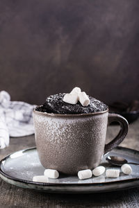 Chocolate cake in a mug with marshmallows and powdered sugar for homemade dessert vertical view