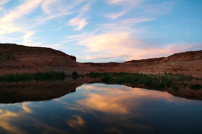 Scenic view of lake by mountains against sky during sunset