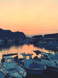 Boats moored at harbor during sunset