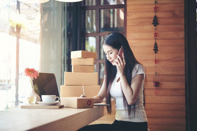 Young woman using mobile phone at table