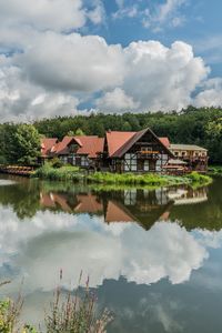 Houses by lake and buildings against sky