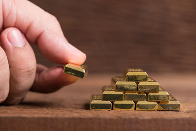 Close-up of hand holding ingot on wooden table