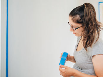 Woman using mobile phone against wall