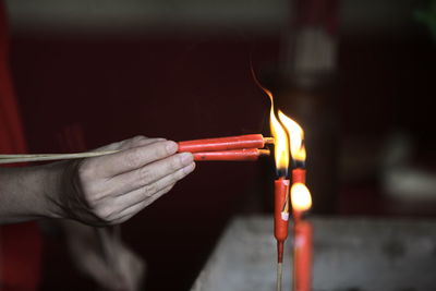 Close-up of hand lighting prayer candles