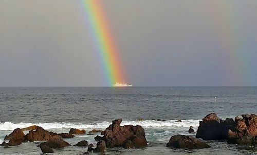 Scenic view of rainbow over sea against sky