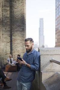 Man using mobile phone while colleagues sitting in background