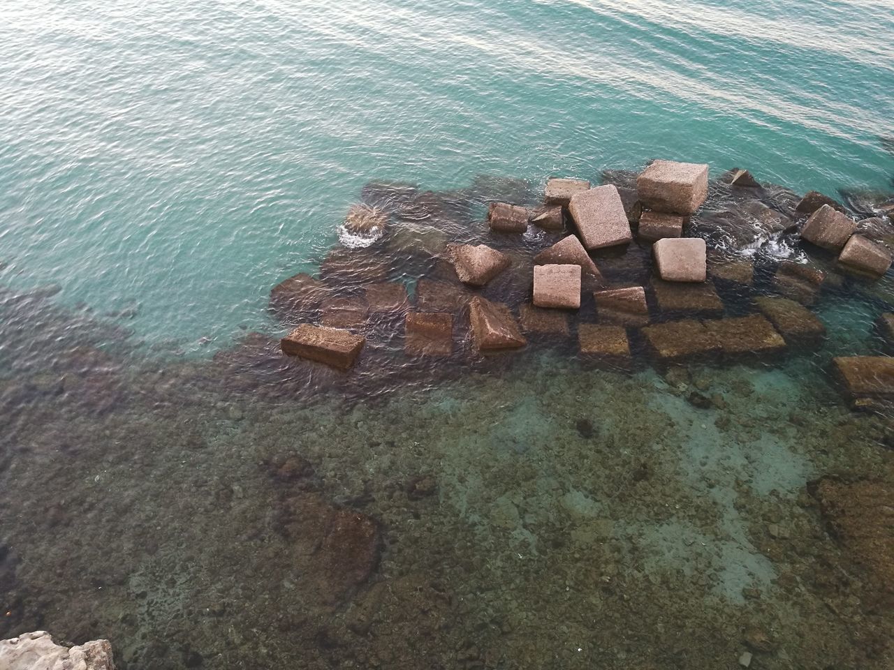 HIGH ANGLE VIEW OF ROCKS AND SEA