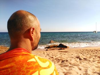 Rear view of man on beach against clear sky