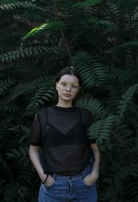 Portrait of young woman standing against plants