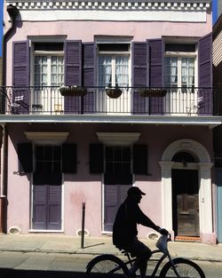 Man riding bicycle on street by building