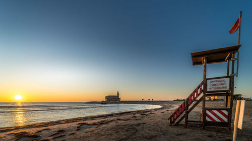 Scenic view of beach against clear sky during sunset