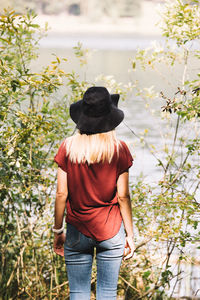 Rear view of woman with umbrella against trees