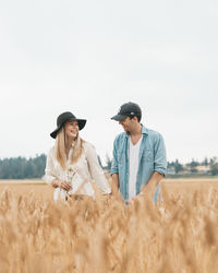 Young man with arms raised on field against sky