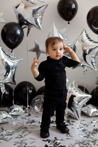 Boy in black clothes on his birthday party with balloon and silver stars