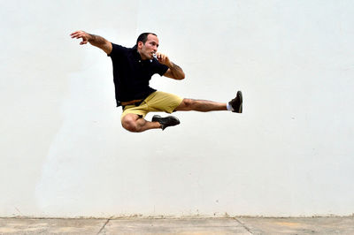 Young man doing a flying kick while eating