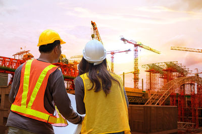 Rear view of people working at construction site against sky