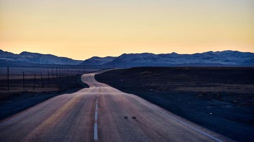 Road amidst landscape against clear sky during sunset