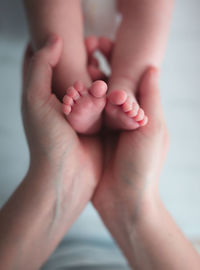 Cropped hands of woman holding baby feet