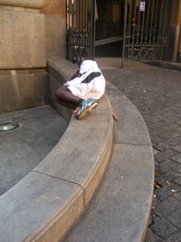 Rear view of man sitting on footpath