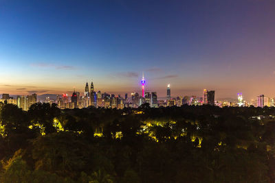 Illuminated buildings in city against sky at night