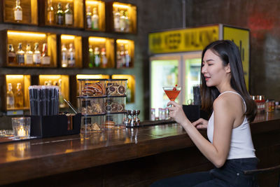 Young woman drinking glass on table at bar