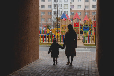 Rear view of women walking on street in city