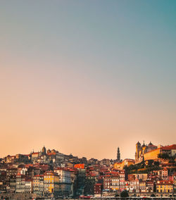 Buildings in city against clear sky during sunset