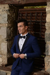 Young man in suit sitting on window sill