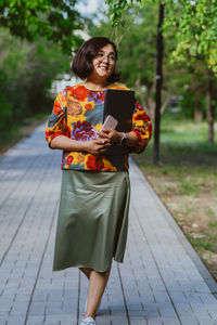 Portrait of young woman standing on footpath