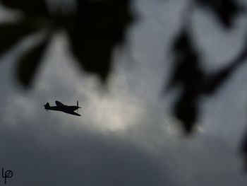 Low angle view of silhouette airplane flying against sky