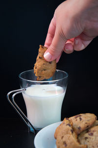 Cropped hand having cookies against black background
