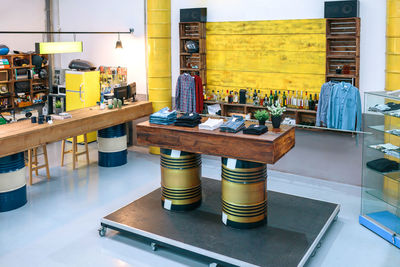 Interior of empty clothing store with clothes on counter over fuel barrels and industrial style