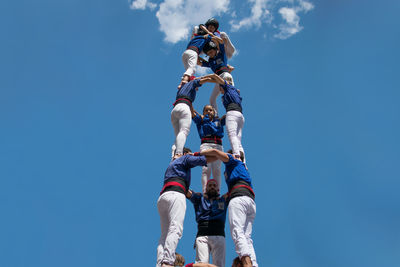 Low angle view of men against blue sky