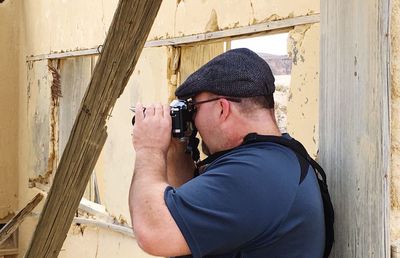 Side view of man photographing in abandoned house