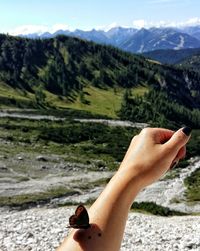 Close-up of woman hand using mobile phone on landscape